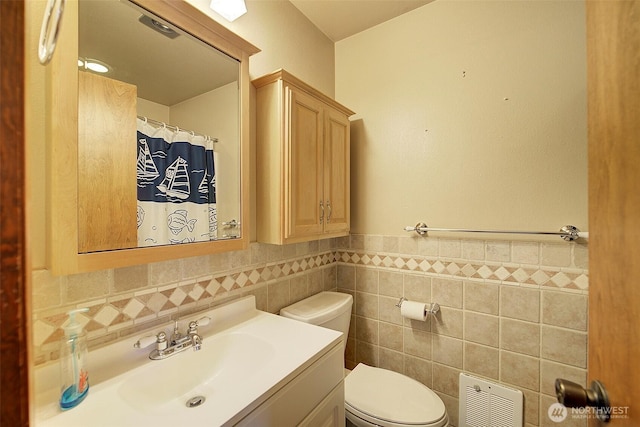 full bathroom with toilet, a wainscoted wall, a shower with curtain, vanity, and tile walls