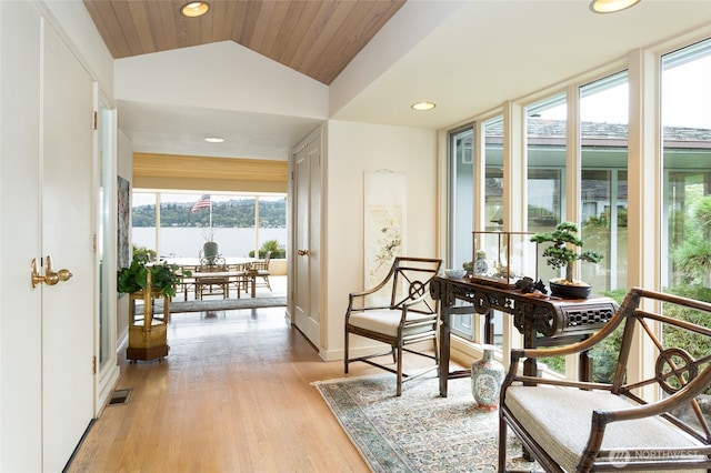 sitting room featuring recessed lighting, a water view, visible vents, light wood-style floors, and vaulted ceiling