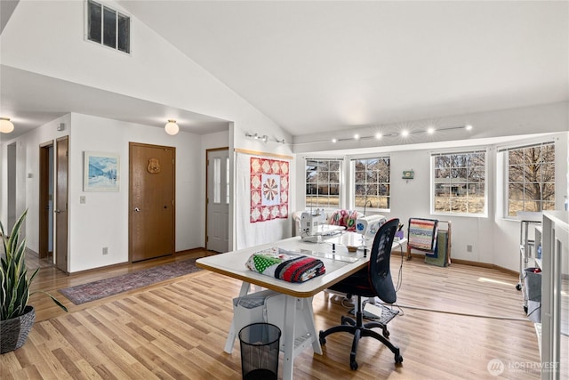 office area with light wood-type flooring, baseboards, visible vents, and vaulted ceiling