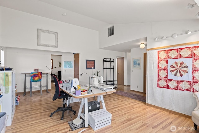 office space with light wood finished floors, visible vents, and high vaulted ceiling