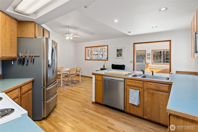 kitchen featuring appliances with stainless steel finishes, brown cabinetry, a sink, and light wood finished floors