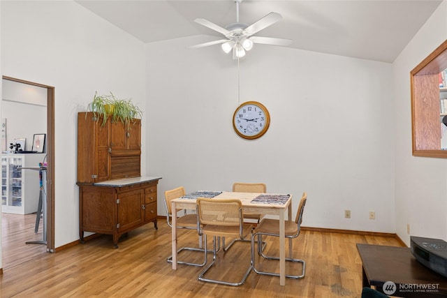 dining area featuring light wood-style floors, baseboards, vaulted ceiling, and a ceiling fan