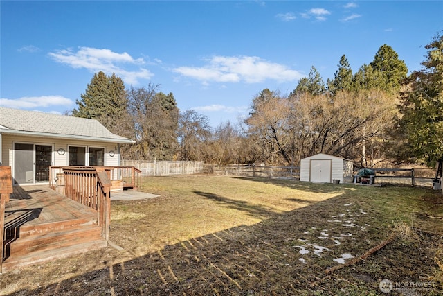 view of yard with a fenced backyard, an outdoor structure, a deck, and a shed