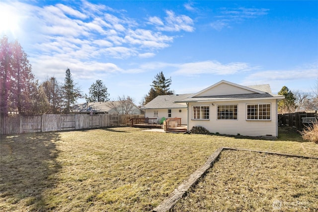 back of house with a fenced backyard, a yard, and a wooden deck