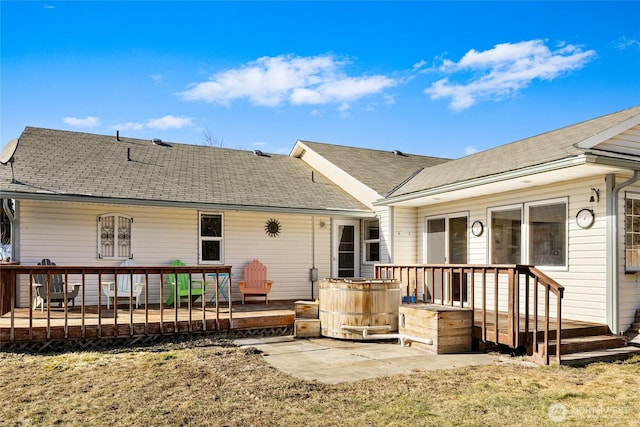 rear view of property featuring a shingled roof, a deck, and a patio