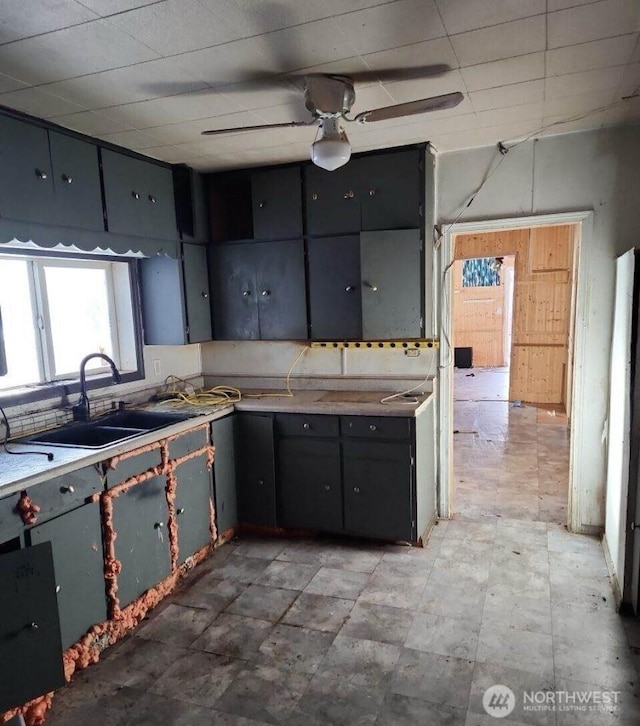 kitchen with ceiling fan, gray cabinetry, a sink, light countertops, and tasteful backsplash