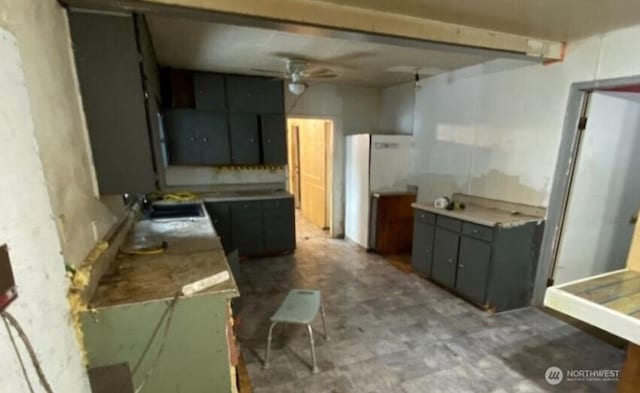 kitchen with a ceiling fan, refrigerator, light countertops, and gray cabinetry