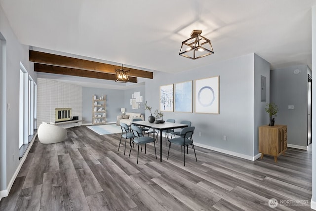 dining area with beam ceiling, a fireplace, baseboards, and wood finished floors