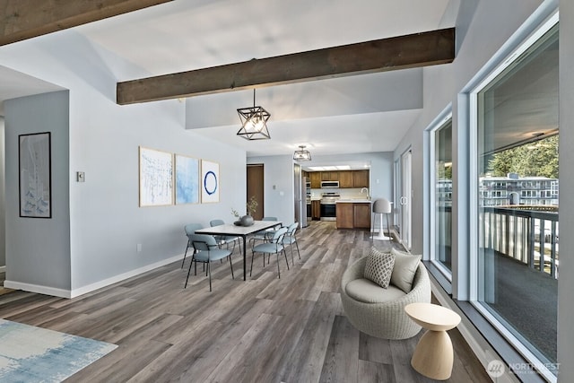 dining area with beamed ceiling, baseboards, and wood finished floors