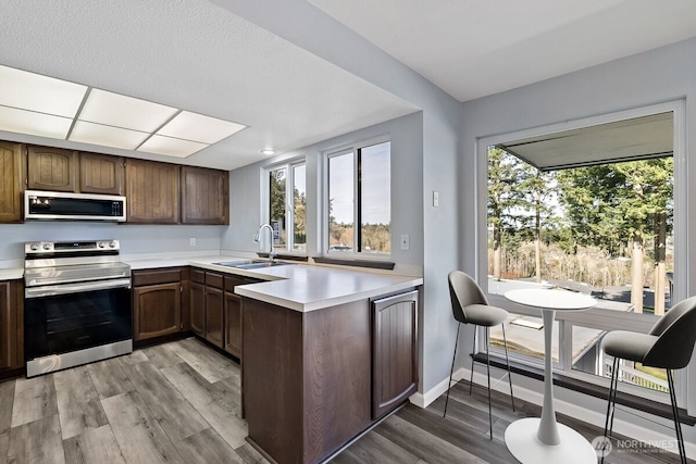 kitchen with light wood-style flooring, stainless steel appliances, a sink, and light countertops