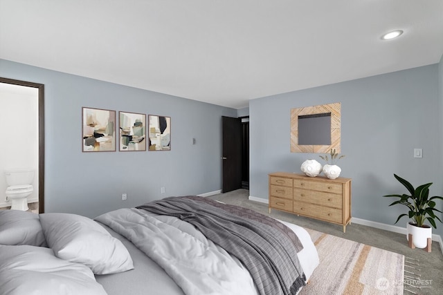 carpeted bedroom featuring ensuite bath and baseboards