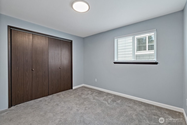 unfurnished bedroom with a closet, carpet flooring, and baseboards