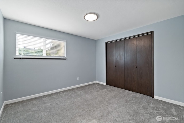 unfurnished bedroom with carpet, baseboards, and a closet