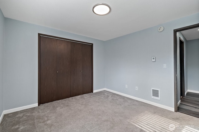 unfurnished bedroom with a closet, carpet, visible vents, and baseboards