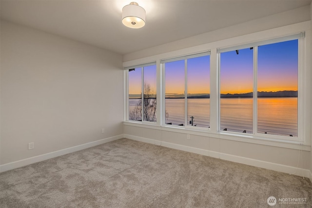 carpeted spare room with a water view and baseboards