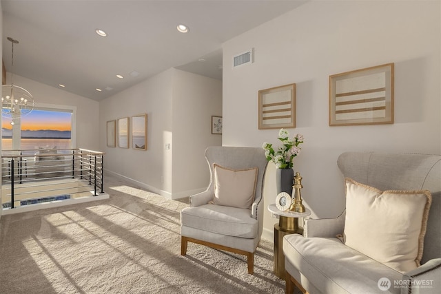 living area featuring a notable chandelier, an upstairs landing, visible vents, vaulted ceiling, and carpet