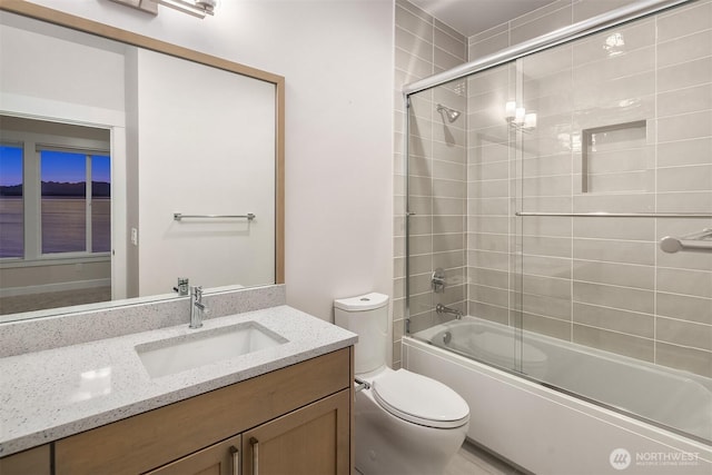 full bath with toilet, bath / shower combo with glass door, and vanity