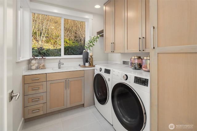 laundry area with a sink, light tile patterned floors, washing machine and dryer, and cabinet space