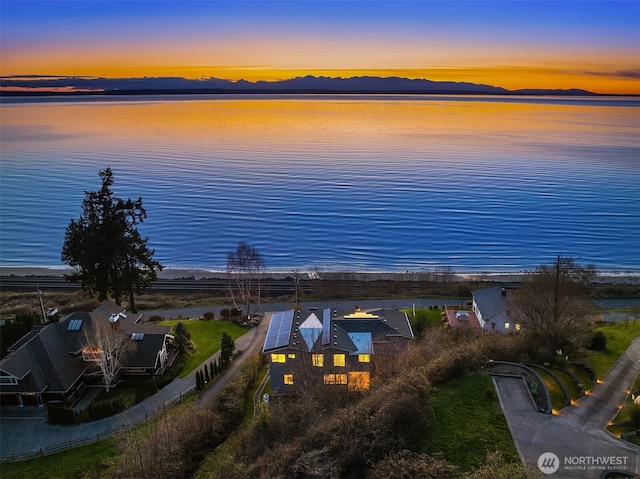 aerial view at dusk featuring a water view