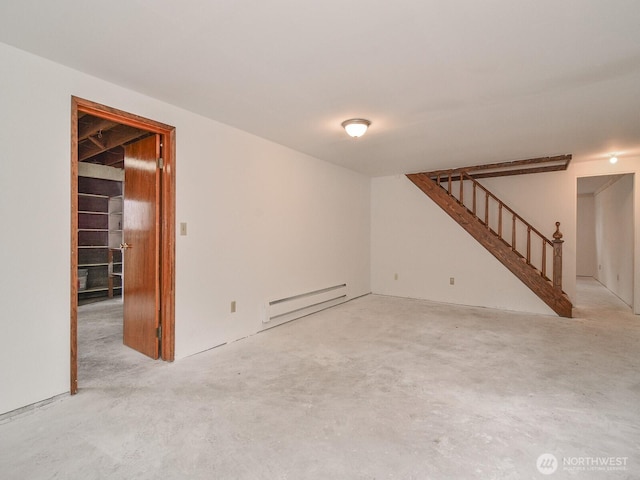 spare room featuring a baseboard heating unit, concrete flooring, and stairway