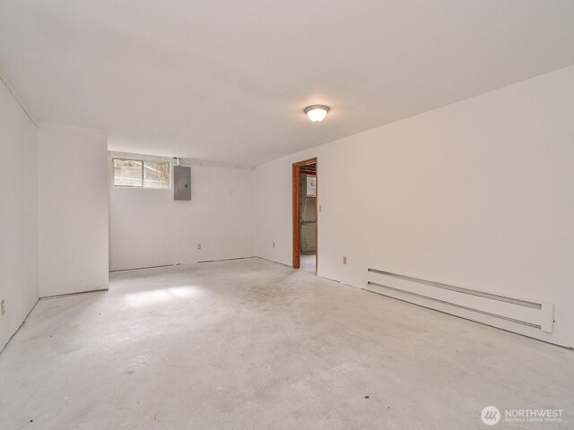 spare room with concrete floors, a baseboard radiator, and electric panel