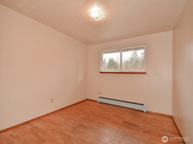 unfurnished room with a textured ceiling, baseboard heating, light wood-style flooring, and baseboards