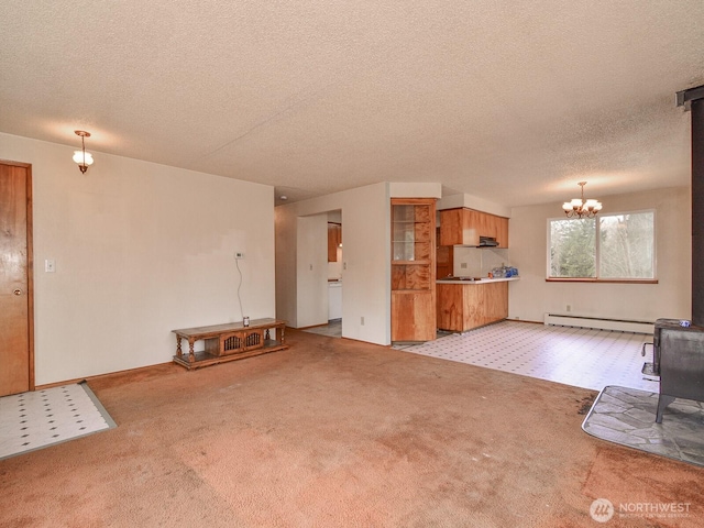 unfurnished living room with a textured ceiling, a chandelier, a baseboard radiator, light carpet, and a wood stove