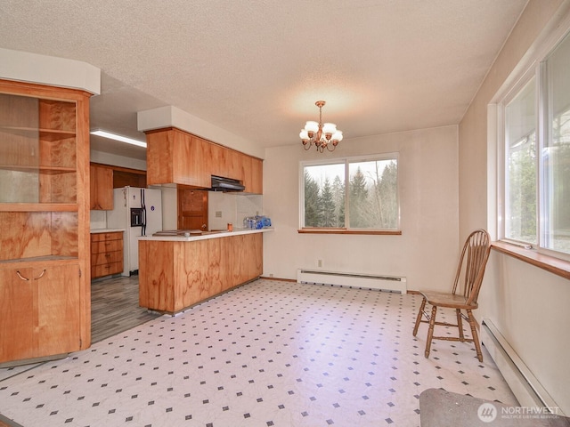 kitchen featuring a chandelier, a baseboard radiator, a baseboard heating unit, a peninsula, and white refrigerator with ice dispenser