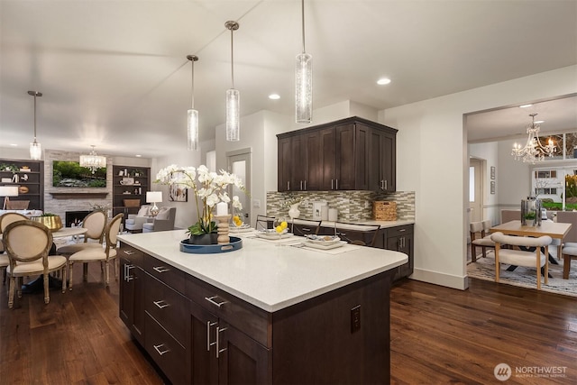 kitchen featuring dark wood finished floors, light countertops, dark brown cabinets, open floor plan, and a large fireplace