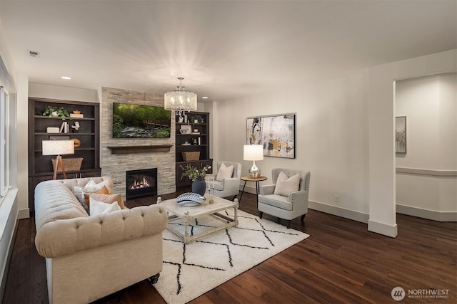 living room featuring built in features, wood finished floors, baseboards, an inviting chandelier, and a fireplace