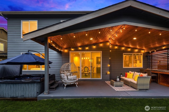 back of house at dusk with a patio, an outdoor hangout area, and a hot tub