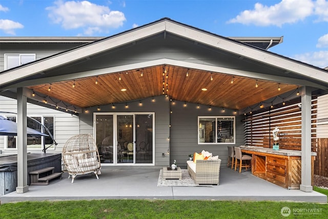 rear view of house with a patio area, an outdoor hangout area, and a hot tub