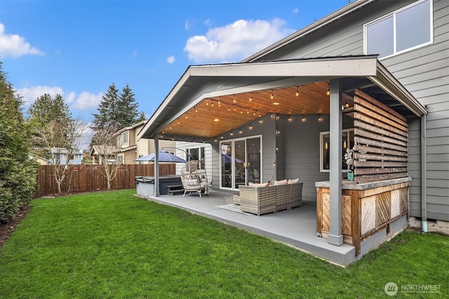 rear view of property with an outdoor living space, a hot tub, a yard, a fenced backyard, and a patio area