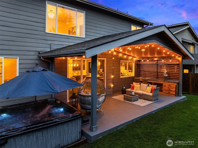 back of house at dusk with roof with shingles, a yard, a hot tub, outdoor lounge area, and a patio area