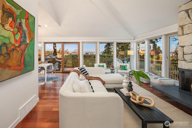 sunroom featuring visible vents, a stone fireplace, and vaulted ceiling