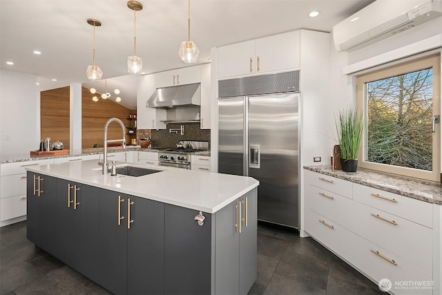 kitchen with under cabinet range hood, an AC wall unit, decorative backsplash, stainless steel appliances, and a sink