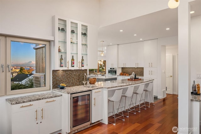 kitchen featuring glass insert cabinets, oven, beverage cooler, dark wood-style floors, and a sink