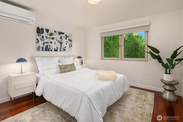 bedroom featuring an AC wall unit, baseboards, and wood finished floors