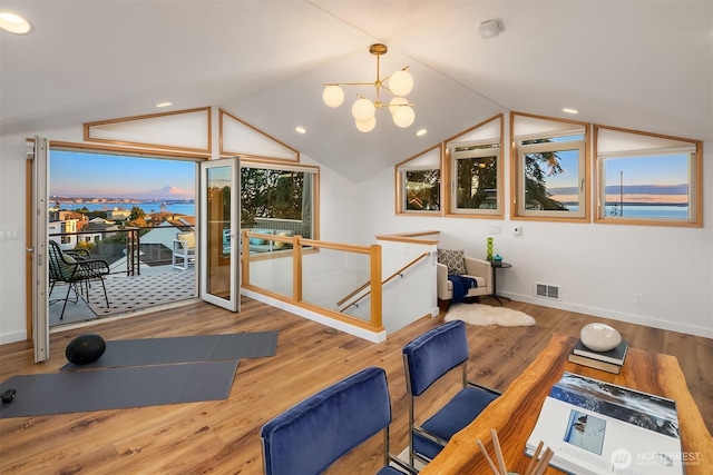 workout area with vaulted ceiling, visible vents, an inviting chandelier, and wood finished floors