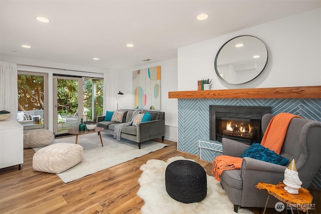 living room featuring recessed lighting, wood finished floors, visible vents, and a tile fireplace