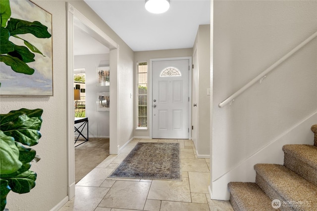 foyer entrance featuring stairs and baseboards