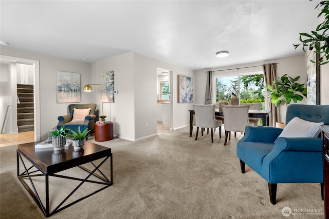 carpeted living area featuring stairway and baseboards