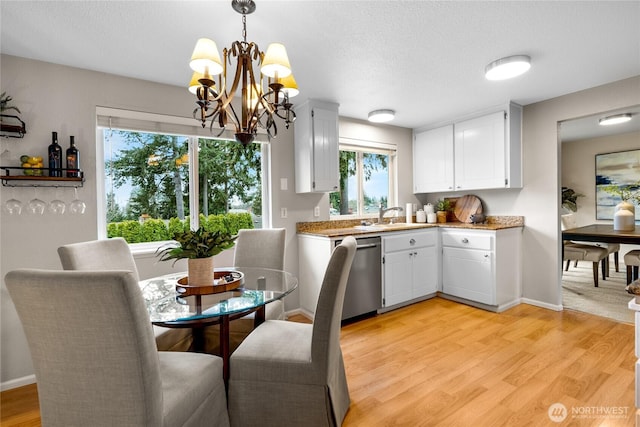 dining room with light wood-style floors, a textured ceiling, baseboards, and a notable chandelier