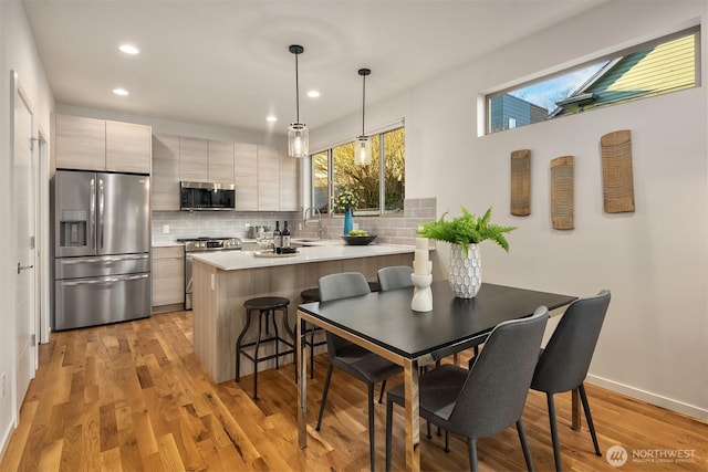 kitchen featuring stainless steel appliances, light wood-style floors, and backsplash