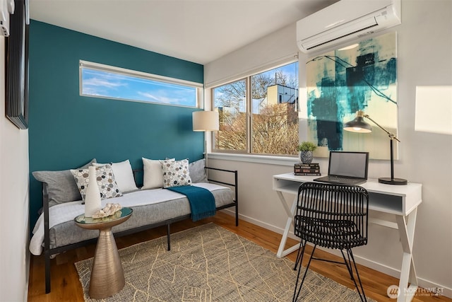 sitting room featuring a wall mounted AC, wood finished floors, and baseboards