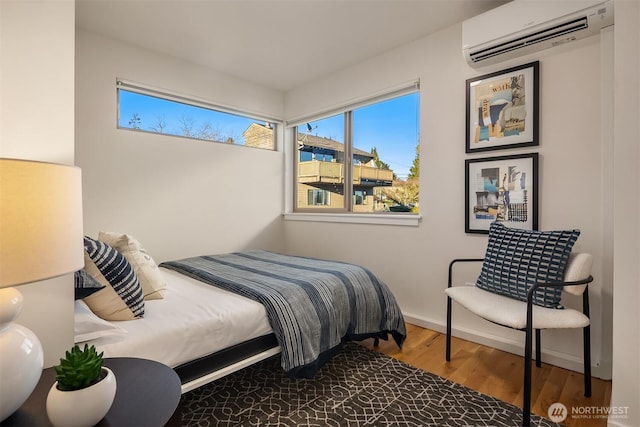 bedroom with wood finished floors and a wall mounted air conditioner