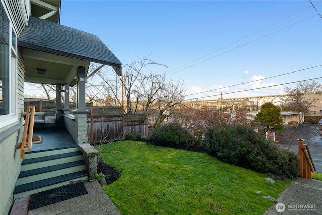 view of yard with covered porch and fence