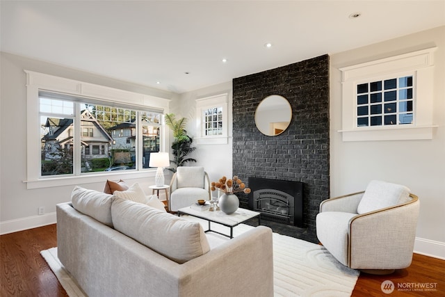 living area featuring recessed lighting, a fireplace, baseboards, and wood finished floors