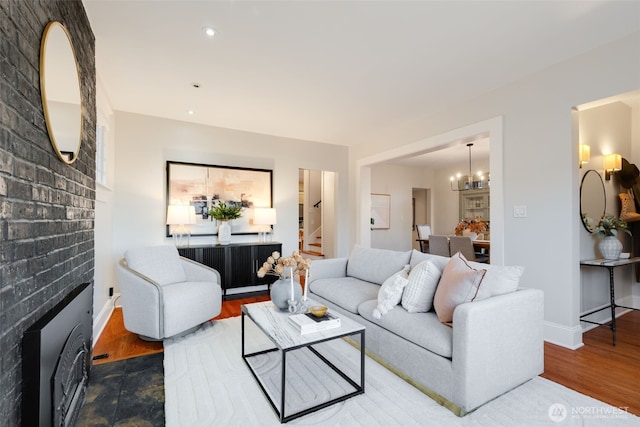 living room featuring baseboards, wood finished floors, stairs, a fireplace, and recessed lighting