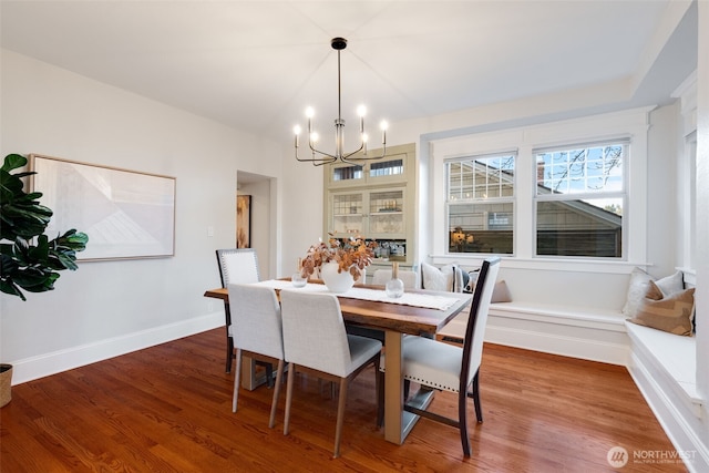 dining space featuring a notable chandelier, baseboards, and wood finished floors